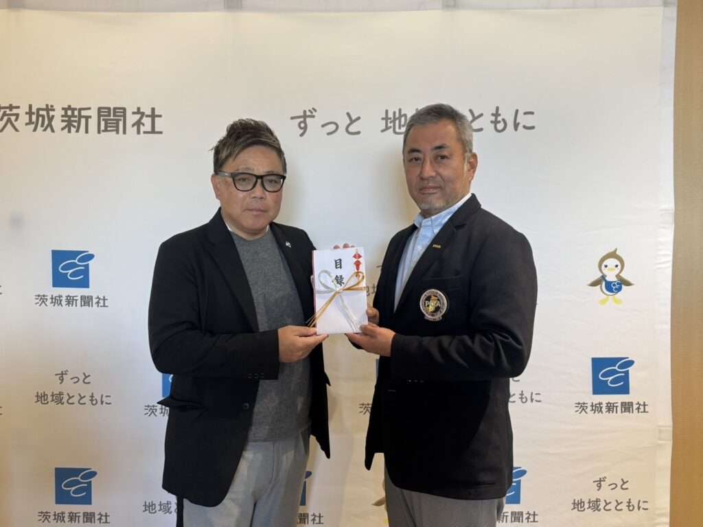 第4回 PGA いばらきチャリティー大会:収支報告と寄付ご報告 茨城新聞社のロゴを背景に、目録を手に並ぶ2人の男性。