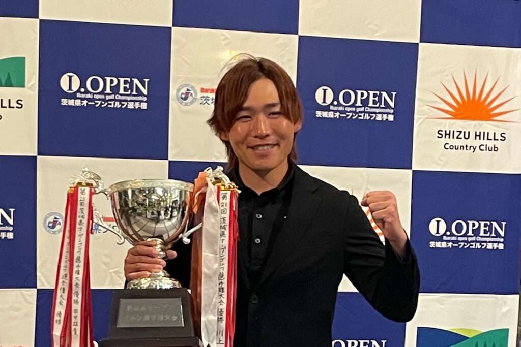 茨城県オープンゴルフ選手権で優勝し、トロフィーを手に笑顔でガッツポーズをする男性。