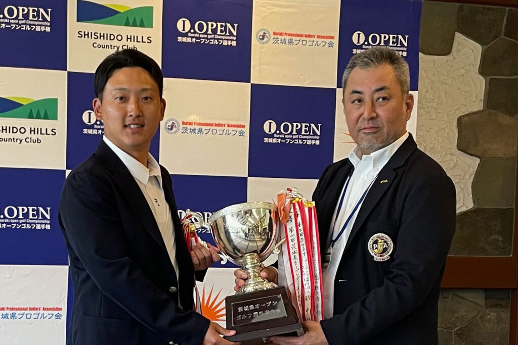 茨城県オープンゴルフ選手権大会の表彰式で、優勝トロフィーを持つ2人の男性。